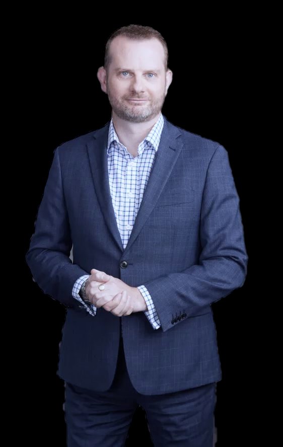 Russell Morris in a navy suit, hands together, looking at the camera